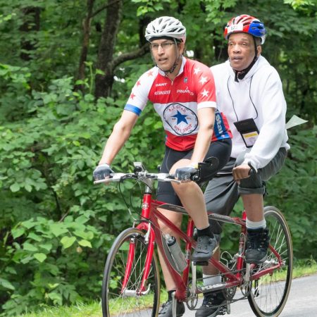 two cyclists riding a tandem cycle