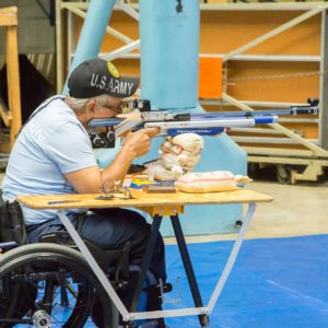 man in wheelchair using a table stand to shoot air rifle