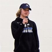 young man wearing baseball cap holding microphone