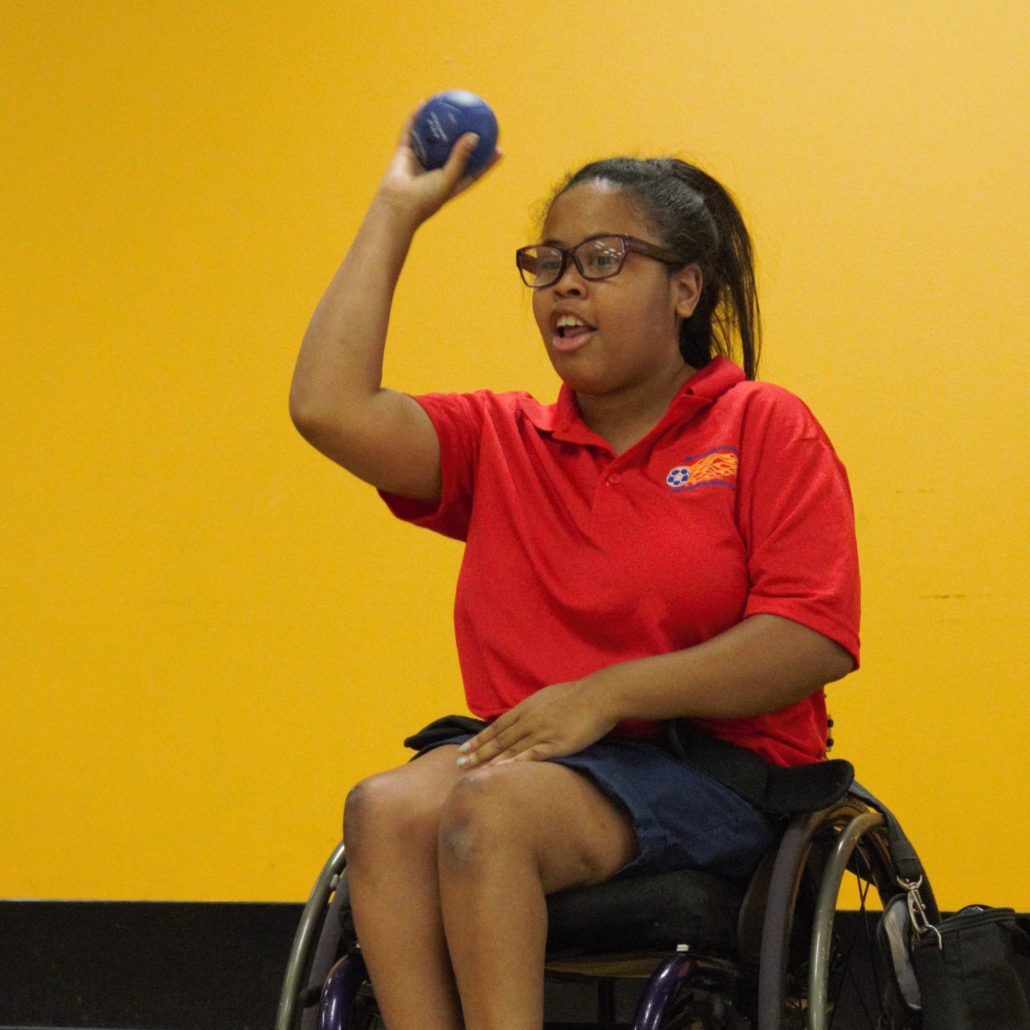 woman in wheelchair preparing to throw a boccia ball