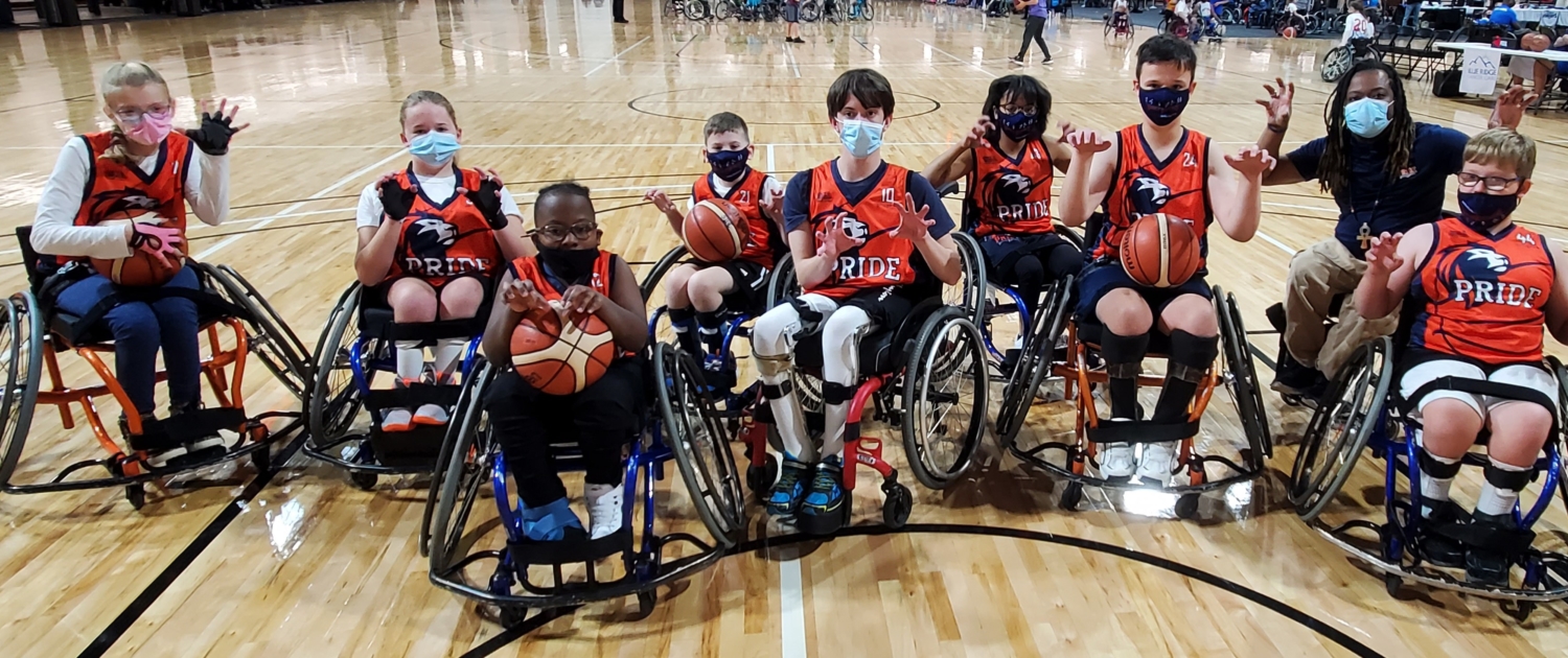 Bridge 2 Sports Team PRIDE varisty youth wheelchair basketball players pose as team with 'paws up' all in sport wheelchairs at tournament