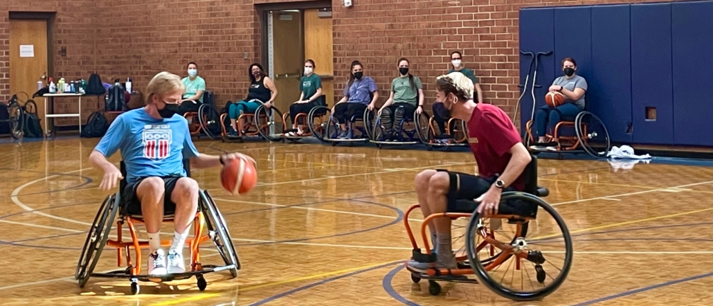 2 college students face one another in sport wheelchair on basetball court