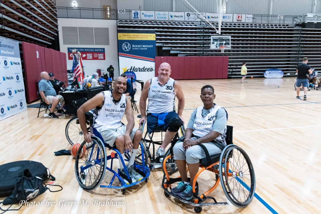 3 wheelchair basketball players, 2 men and 1 woman, pose for a team shot at the Valor Games Southeast 2022 3 on 3 wheelchair basktball tournament