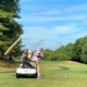 with blue sky above and man hits a drive on golf course from a solo rider adapted cart